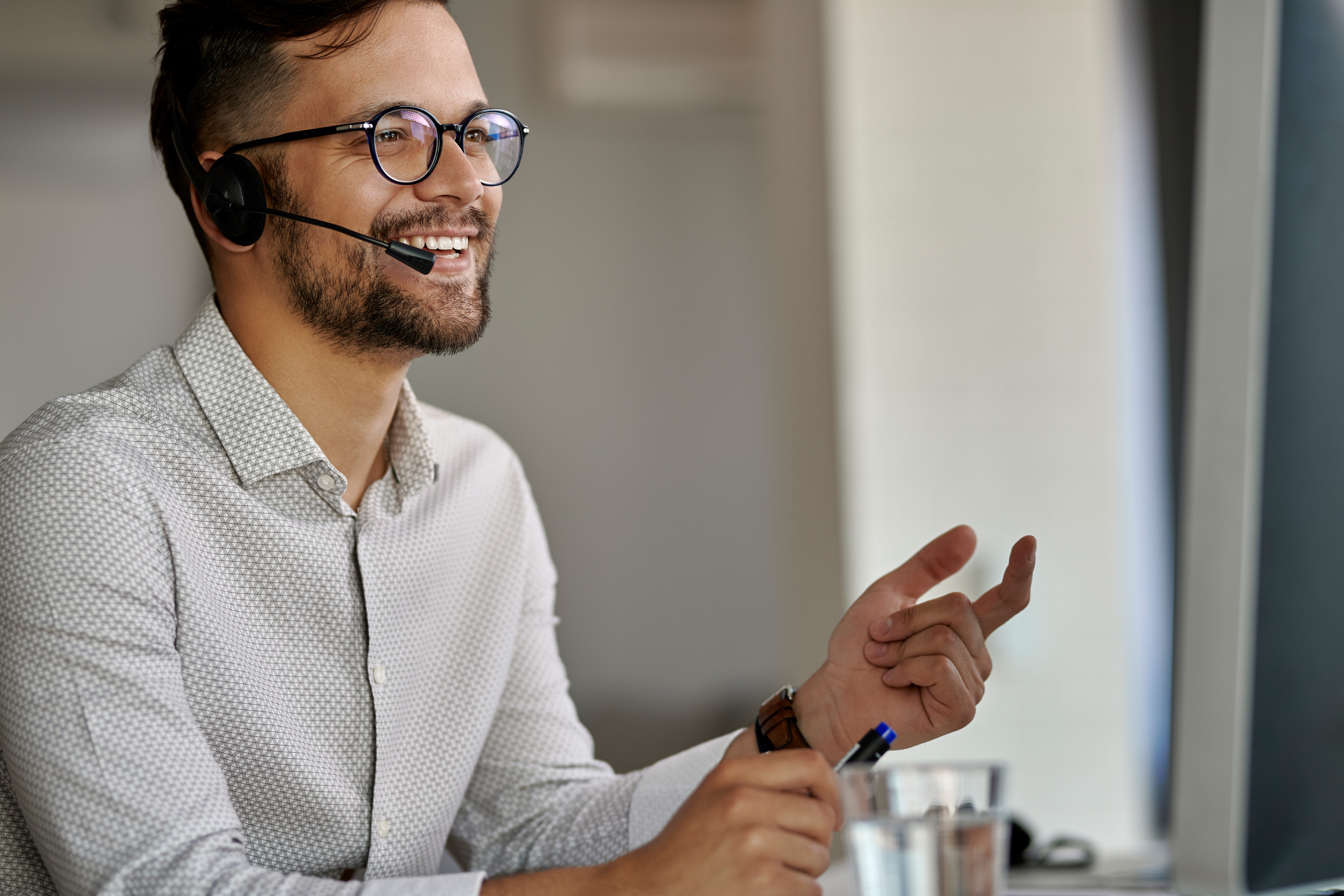 Happy call center agent using computer while communicating with clients and working in the office.
